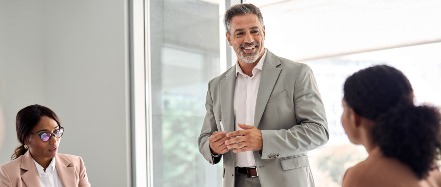 Busy older leader and company employees at business meeting discussing work.
